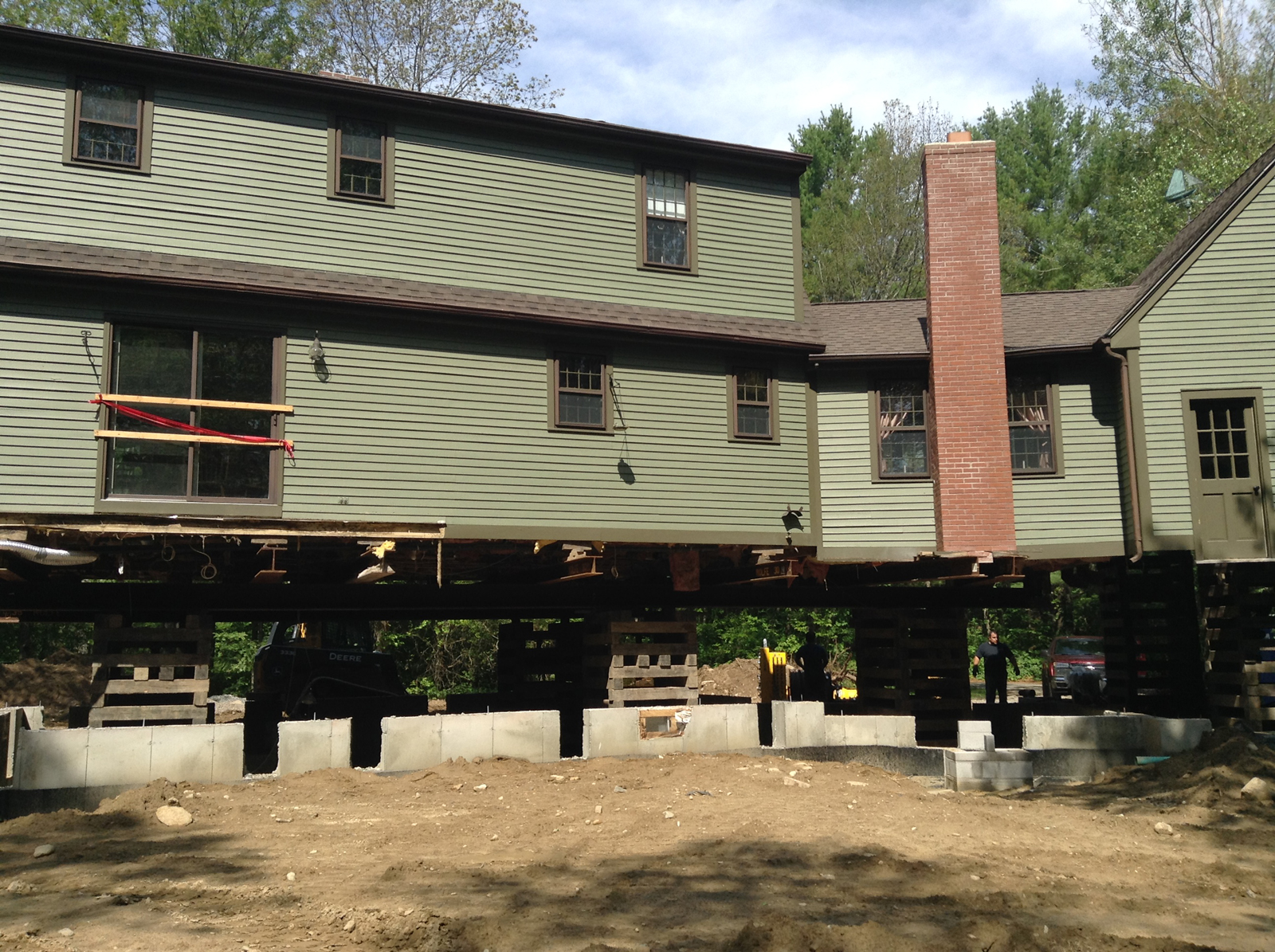 a home lifted up with workers replacing the foundation