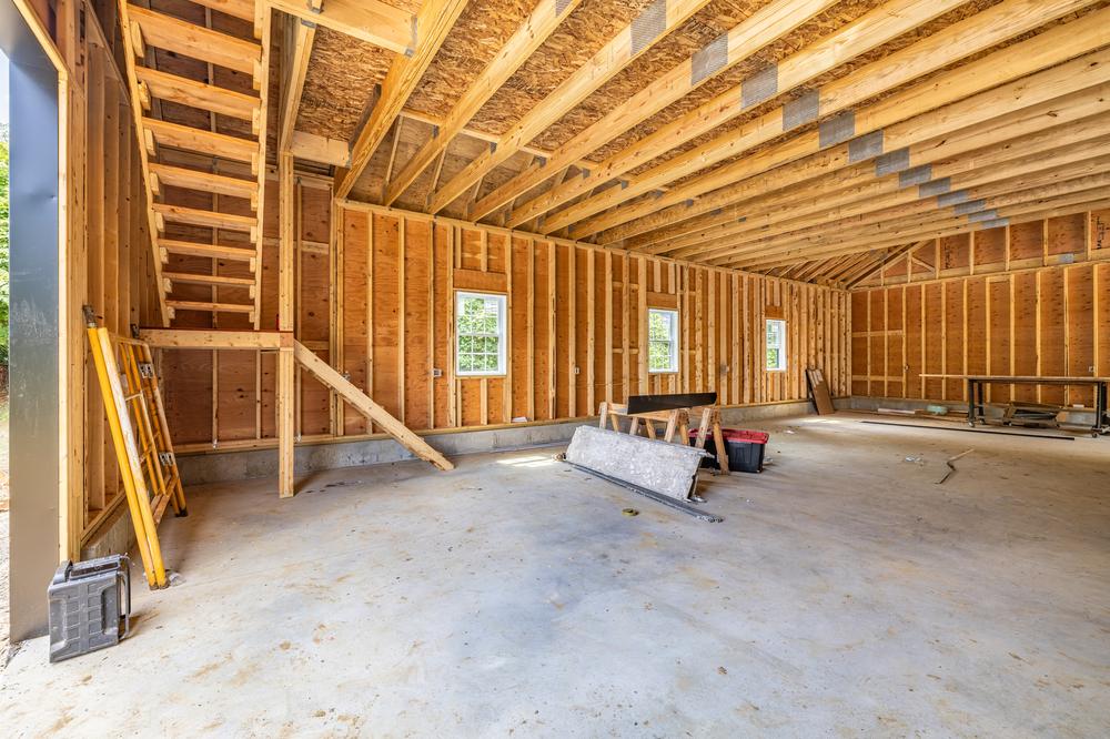 Interior view of commercial construction showing exposed wood framing, roof trusses, and concrete slab during an active post-frame building build-out.
