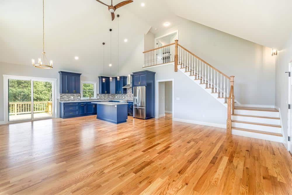 Open-concept living space featuring a modern kitchen renovation with blue cabinetry, hardwood floors, and staircase, highlighting quality residential construction and custom interior craftsmanship.