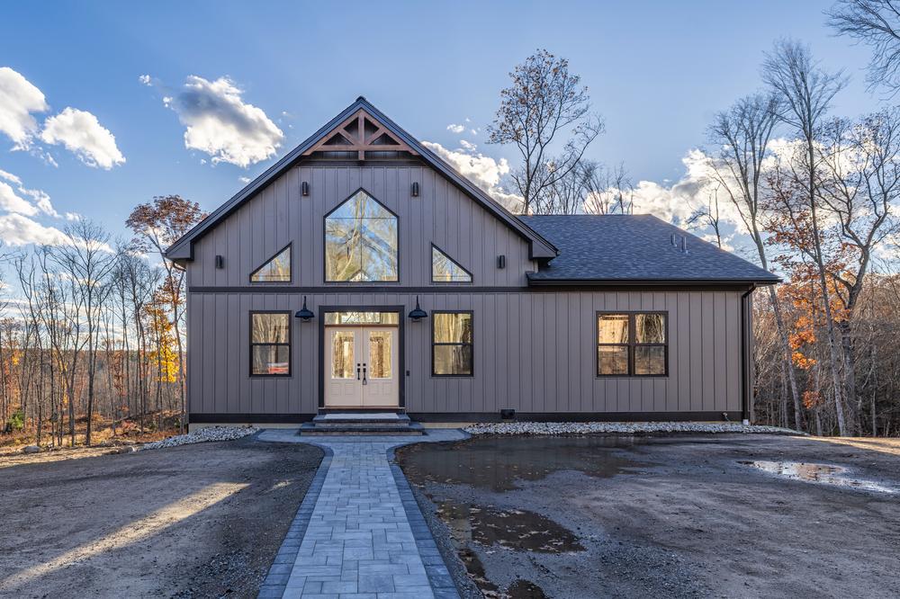 Residential construction interior showing a finished two-car garage with smooth concrete flooring, insulated walls, modern overhead door system, and natural light from side windows.