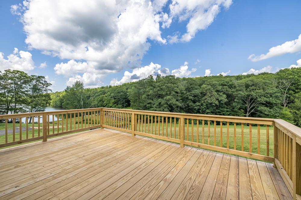 Residential construction deck featuring a newly built wooden outdoor deck with railing and scenic views of a wooded landscape, highlighting quality residential construction and outdoor living space.