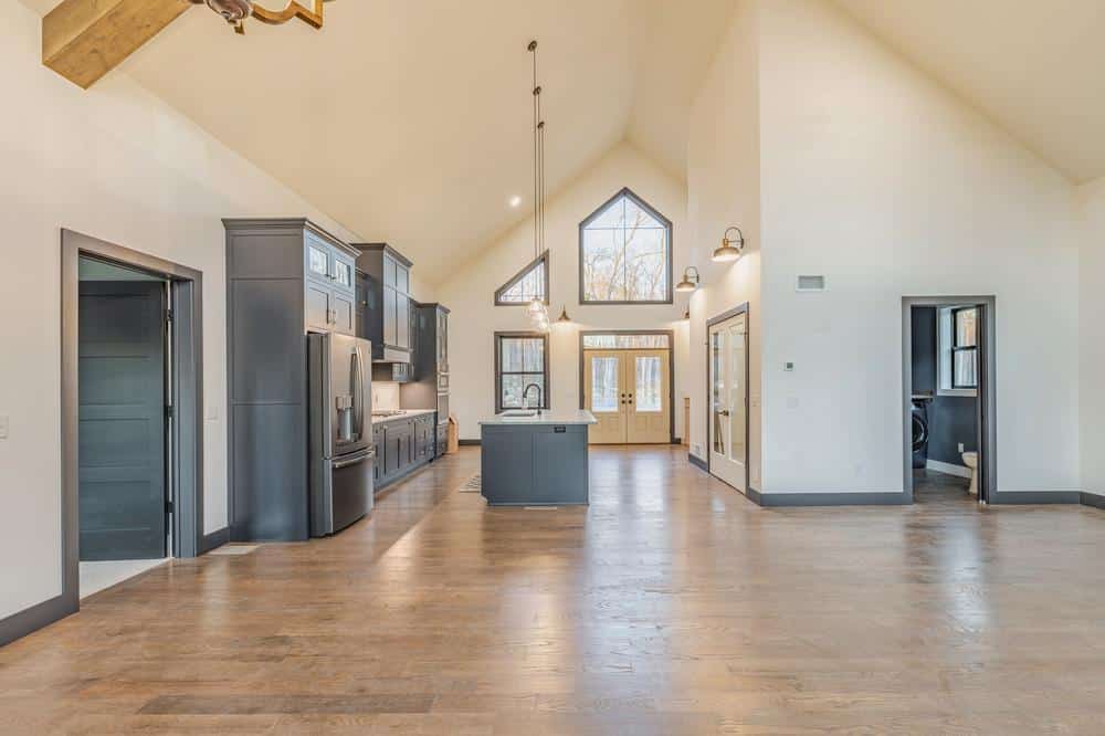 Residential construction interior featuring an open-concept kitchen renovation with custom cabinetry, center island, vaulted ceilings, and hardwood flooring.